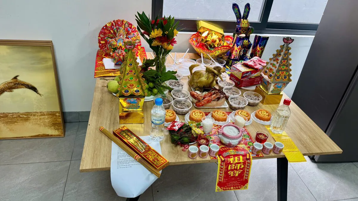 Mâm cúng trên bàn gỗ cạnh cửa sổ gồm cặp tháp Kim Sơn Ngân Sơn vàng bạc, gà trống luộc, tôm càng tam sên, 5 đĩa xôi gấc chữ Lộc, 6 chén chè đậu và bộ mão Quan Lớn