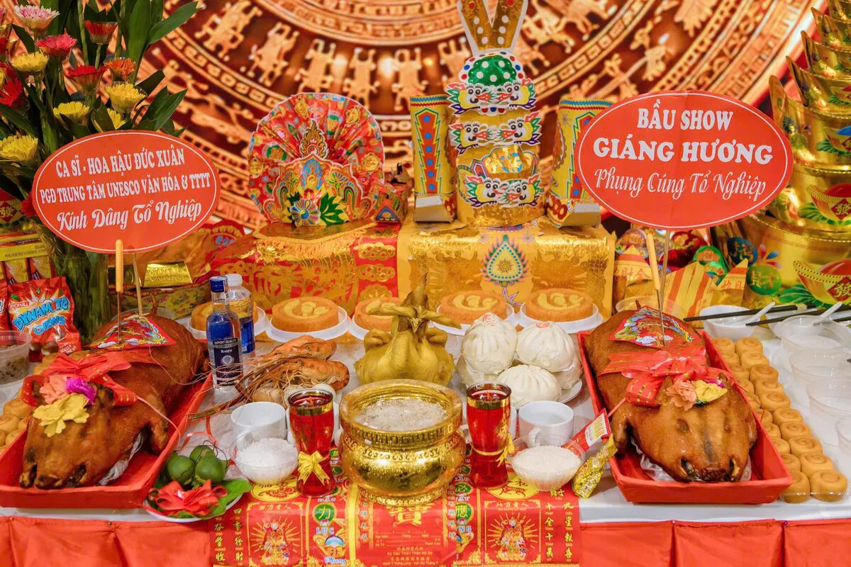 Cận cảnh bàn đại lễ Giỗ Tổ Sân Khấu có bảng tên Ca sĩ Hoa hậu Đức Xuân và Bầu show Giáng Hương với 2 con heo sữa quay nguyên con, gà trống luộc, tôm càng, bánh bao, xôi gấc và mão Tổ Nghiệp